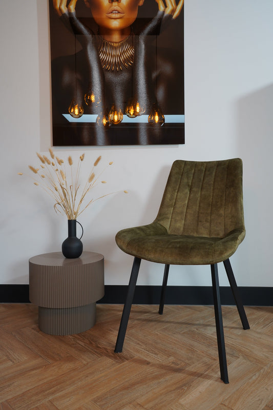 Eetkamerstoel Marilène velvet in groen met strakke, rechthoekige poten, naast bijzettafel en kunstwerk, model 2025.